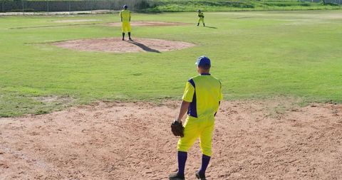 Amateur Baseball Teammates Standing on Infield Preparing for Pitch in Yellow Uniforms