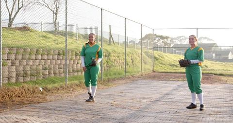 Diverse softball teammates in green and yellow uniforms