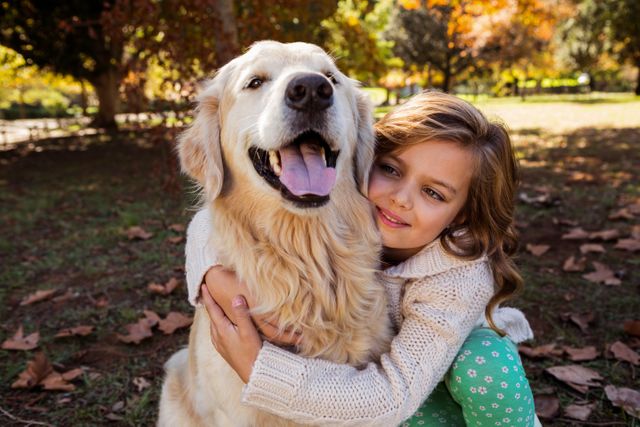 Little girl hugging her golden retriever in a park during autumn. The scene captures a moment of joy and companionship, with fallen leaves and vibrant colors in the background. Ideal for use in advertisements, family-oriented content, pet care promotions, and articles about the bond between children and pets.
