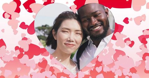 Multicultural couple smiling in heart cutout with red hearts valentine romance outdoor portrait