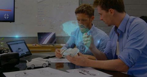 Automotive designers inspecting scale car prototype and ar rendering while collaborating