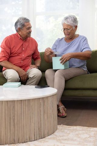 Senior couple sharing emotional moment with woman opening heartfelt card from light-blue gift box