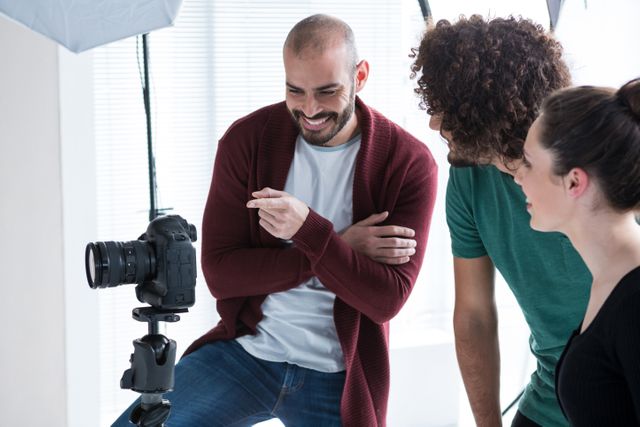 Photographer and colleagues reviewing shots on camera in a modern studio. Ideal for concepts related to teamwork, collaboration, professional photography, creative workspaces, and technology in the workplace.