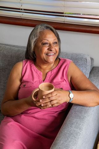 Senior Woman Relaxing with Mug on Comfortable Sofa