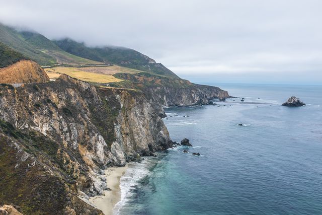 Showcases the dramatic coastal cliffs and ocean waves of Big Sur, California. Ideal for use in articles about natural beauty, travel and tourism promotion, outdoor activities, and California tourism. Perfect for emphasizing scenic views and tranquility in nature-themed content.