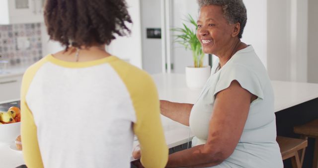 Happy senior african american woman talking with adult daughter at home. senior healthcare and medical physiotherapy treatment.