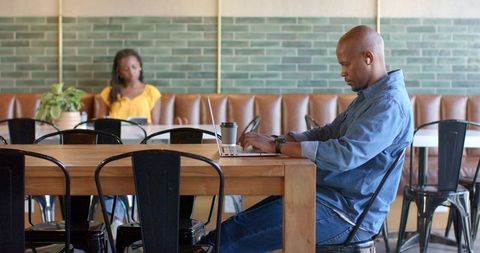 Focused remote work in cafe: african american man typing on laptop, coworking lifestyle