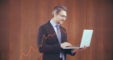 Executive typing on laptop with rising financial charts overlay for corporate reports