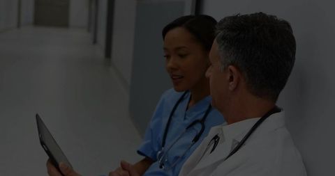 Doctor and Nurse Collaborate in Hospital Corridor with Tablet