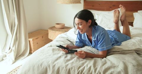Woman Shopping Online Comfortably in Pajamas on Bed
