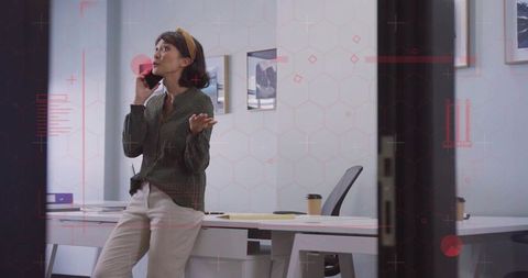 Asian Woman Engaged in Phone Call at Modern Office Workspace