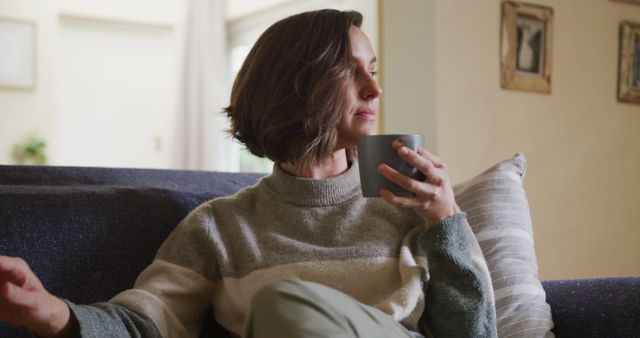 Caucasian woman stroking her pet dog sitting on sofa at home. lifestyle, pet, companionship and animal friendship concept.