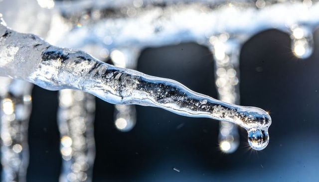 Sunlit icicle droplet macro with bokeh sparkle, frost bubbles and crystal texture