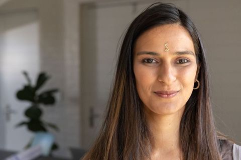 Indian woman making eye contact with camera wearing forehead jewel and gold hoop earrings
