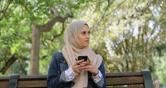 Muslim Woman in Hijab Sitting on Park Bench Using Smartphone - Download Free Stock Images Pikwizard.com