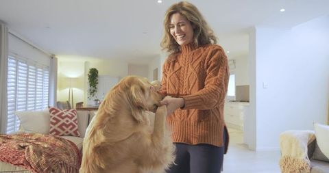 Woman enjoying quality time with happy golden retriever in cozy living room