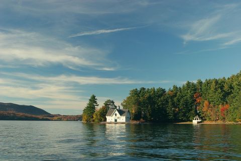 White boathouse sitting on tranquil forest lake with autumn foliage and waterfront gazebo