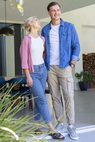 Young couple standing on threshold leaning and smiling, enjoying modern patio lifestyle