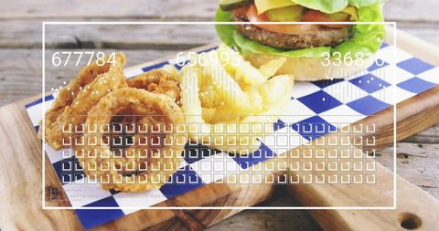 Serving beef burger with onion rings and fries on wooden board closeup for casual dining