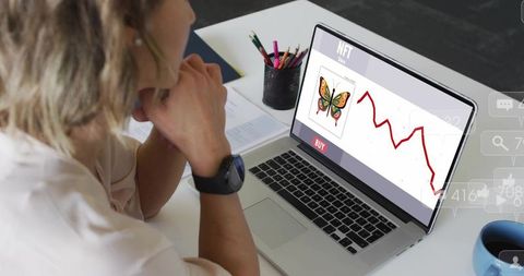 Woman viewing NFT marketplace on laptop with falling price chart, clasping chin at desk