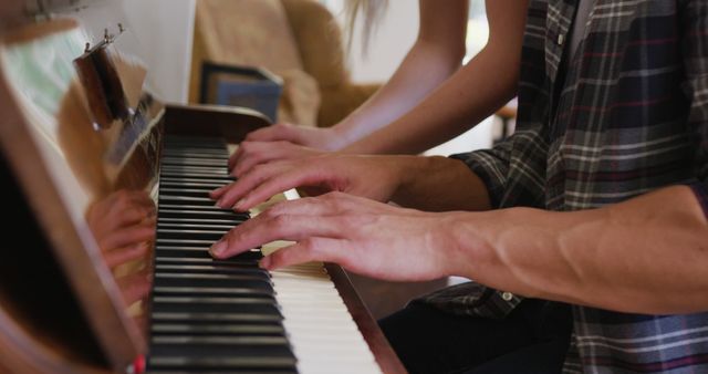 Hands playing piano together, suggesting a collaborative learning experience. Useful for promoting music lessons, learning materials, or any education-related content that highlights unity and teamwork.