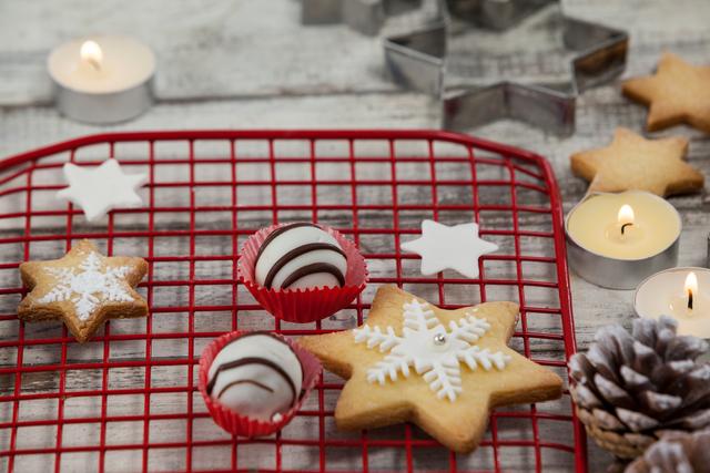 Christmas-themed cookies and candles on a rustic wooden table. Ideal for holiday baking blogs, festive greeting cards, and seasonal advertisements. The warm, cozy atmosphere makes it perfect for promoting winter celebrations and homemade treats.