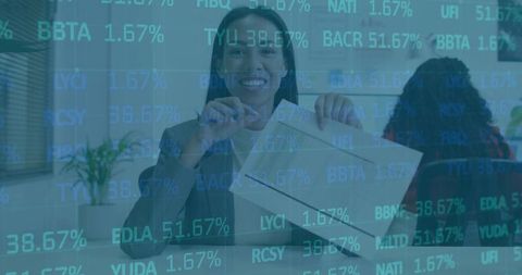 Smiling professional opening small package at office with stock market ticker overlay