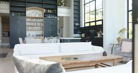 Sunlit contemporary open-plan living room with white slipcovered sofa and rustic wood coffee table