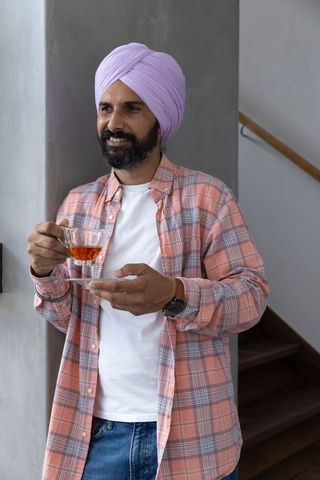Casual elegance: indian man relaxing with tea in modern home interior