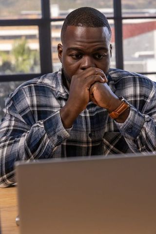 Man deep in thought at modern office desk with laptop