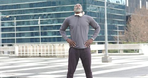 Mature african american man standing confidently on urban crosswalk wearing headphones