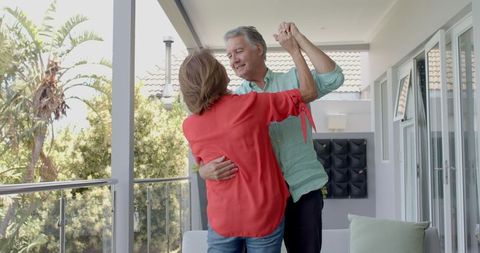 Joyful Senior Couple Dancing on Sunny Balcony