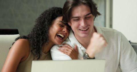 Joyful couple interacting with laptop in modern home