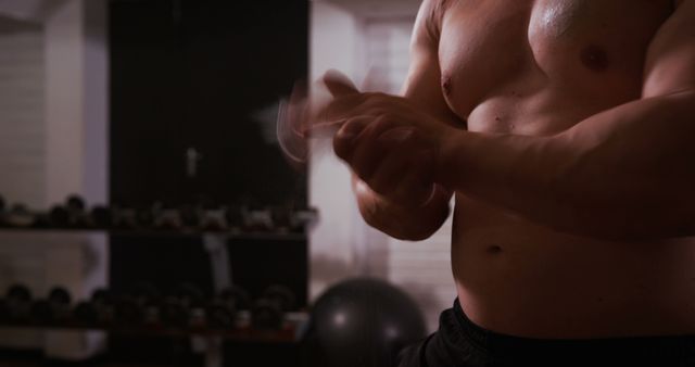 Muscular man clapping chalked hands in gym, preparing for workout. Ideal for fitness blogs, training programs, motivational posters, and advertisements for gym equipment or sportswear.