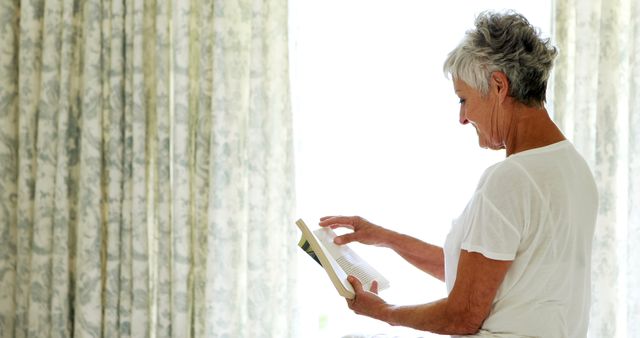 Senior Woman Relaxing While Reading Book at Home Near Window - Download Free Stock Images Pikwizard.com