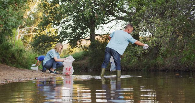 A multi-ethnic group of adult conservation volunteers cleaning up a river on a sunny day in the countryside, picking up rubbish. Ecology and social responsibility in a rural environment.
