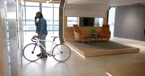 Professional Male with Bicycle Communicating in Modern Office - Download Free Stock Images Pikwizard.com