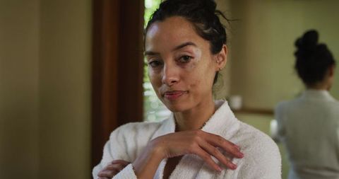 Relaxed biracial woman in white robe inspiring self-care moments