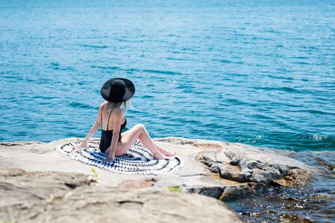 Woman in Swimsuit Relaxing on Rocky Beachfront