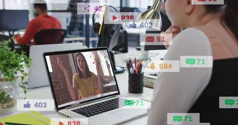 Woman video chatting at office desk with social media notifications and team collaboration