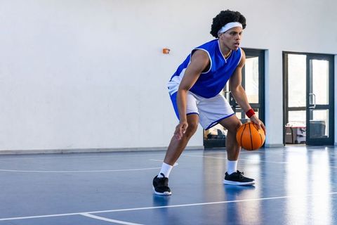 Young Athlete Dribbling Basketball in Indoor Gym
