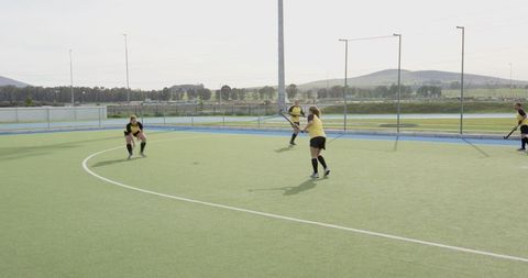 Female field hockey players preparing interception on artificial turf near semicircle