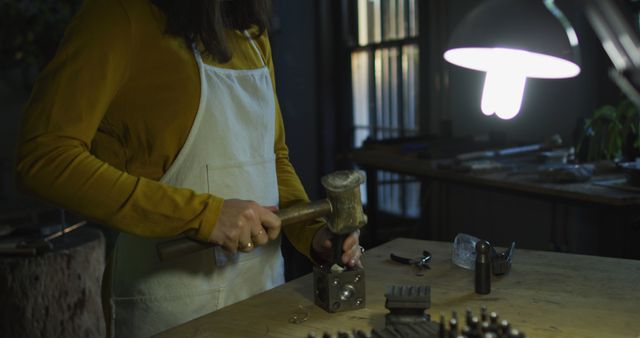 Craftsperson Working in Dimly Lit Workshop with Hammer - Download Free Stock Images Pikwizard.com