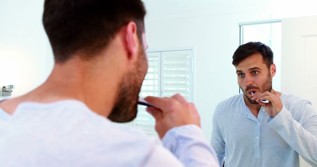 Man brushing teeth while looking in bathroom mirror - Download Free Stock Images Pikwizard.com