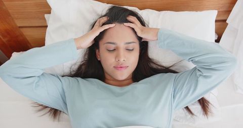 Relaxed woman resting with hands on head in tranquil bedroom setting