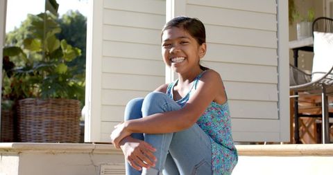 Smiling girl relaxing on sunlit porch steps