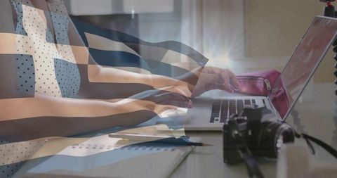 Professional woman typing with greek flag overlay on laptop at office