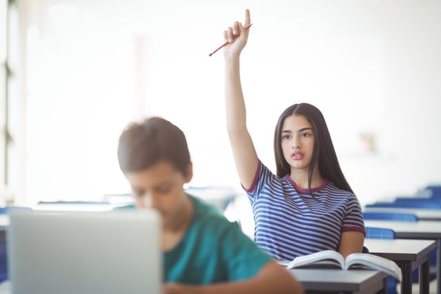 Schoolgirl raising hand in classroom, showing engagement and eagerness to participate. Ideal for educational materials, school brochures, and articles on student engagement and classroom dynamics.