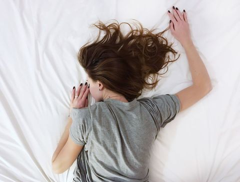 Young Woman Relaxing on White Bed Enjoying Peaceful Sleep