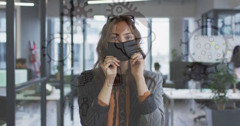 Businesswoman with Face Mask and Medical Icons Overlay in Office